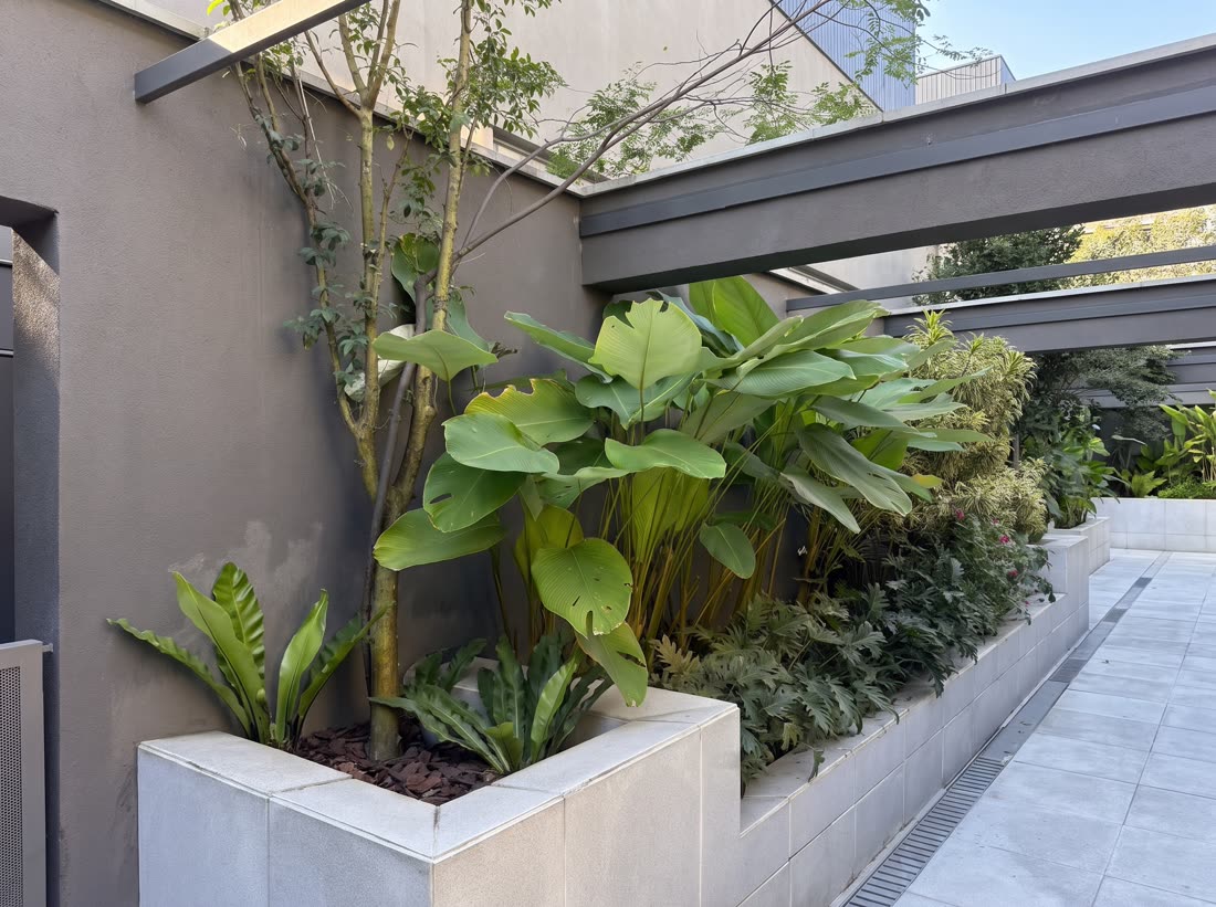 Paisagismo corporativo com jardineiras integradas ao corredor externo de prédio comercial